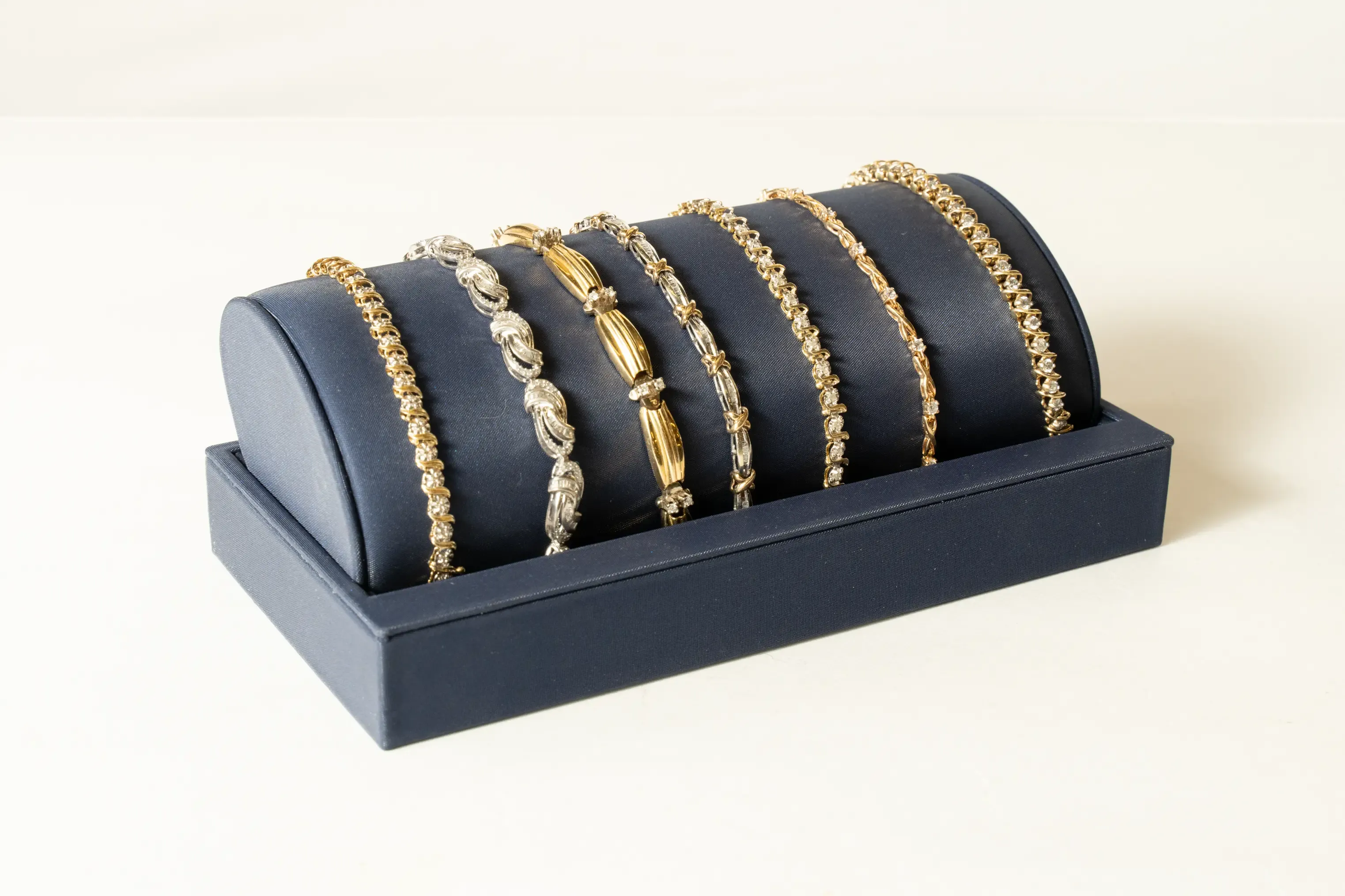 Several gold bracelets displayed on a jewelry stand.
