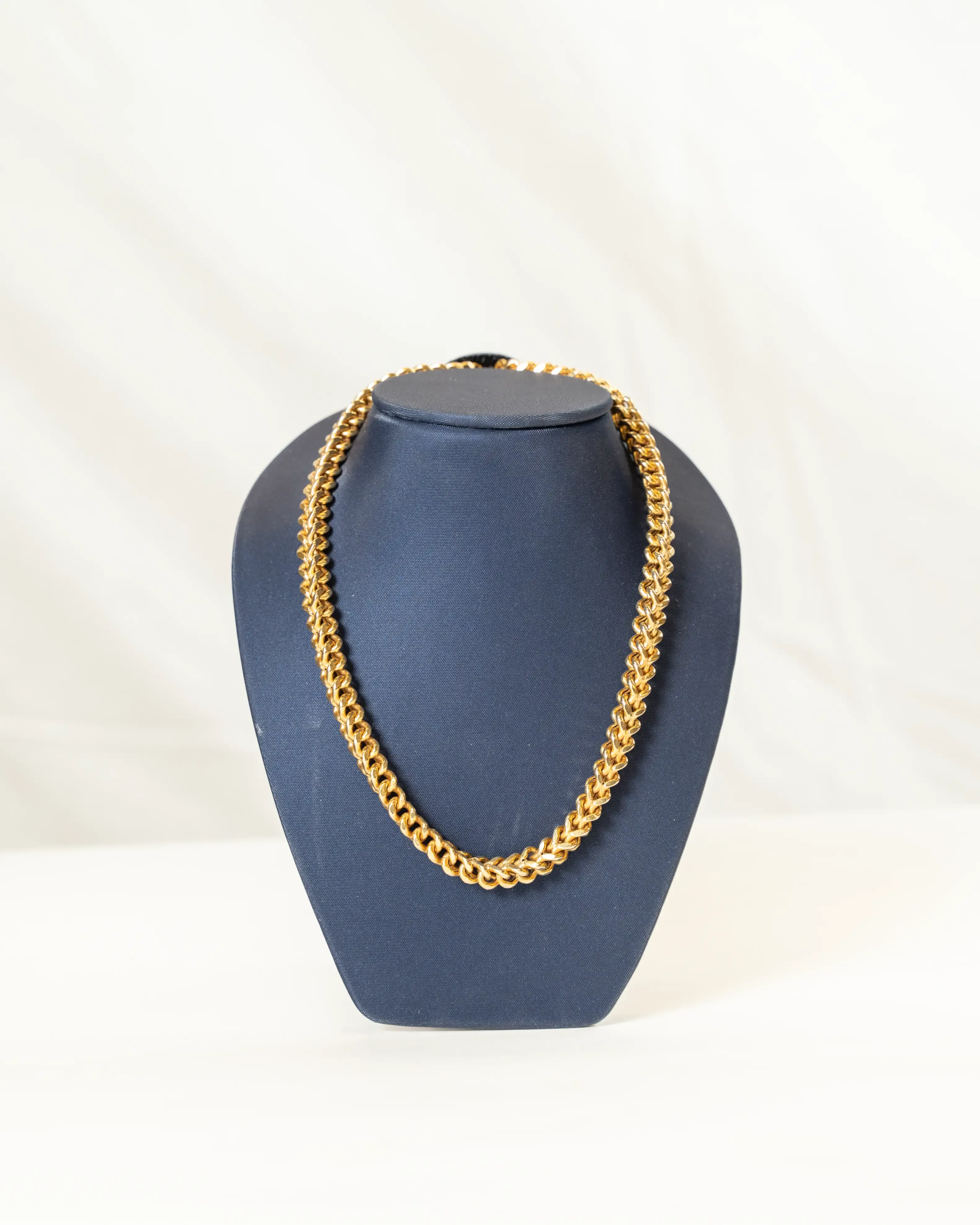 Thick gold chain necklace displayed on a dark blue mannequin bust against a light background.