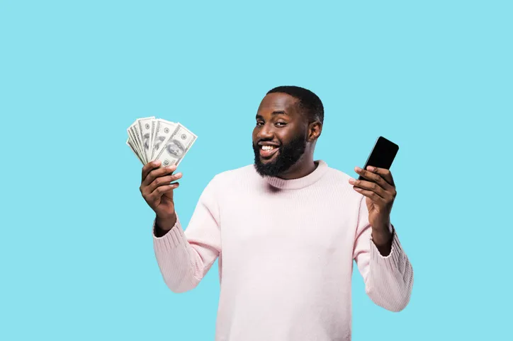 Displays a man holding cash and a phone, indicating successful financial dealings or quick cash solutions.