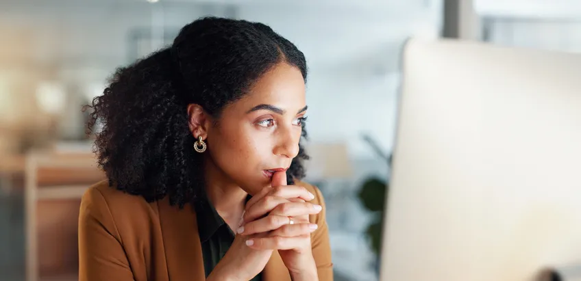 Shows a woman intently focused on a computer screen, suggesting work, research, or financial planning.